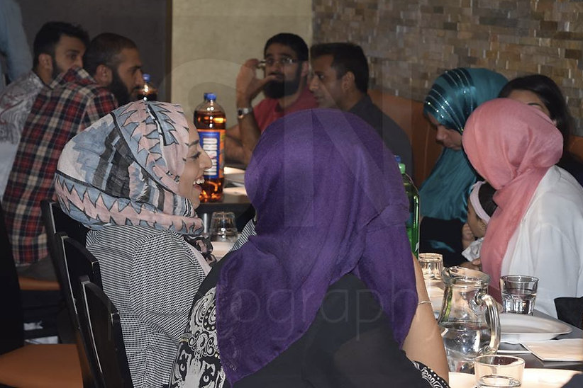 A group of adults sitting at tables containing drinks.